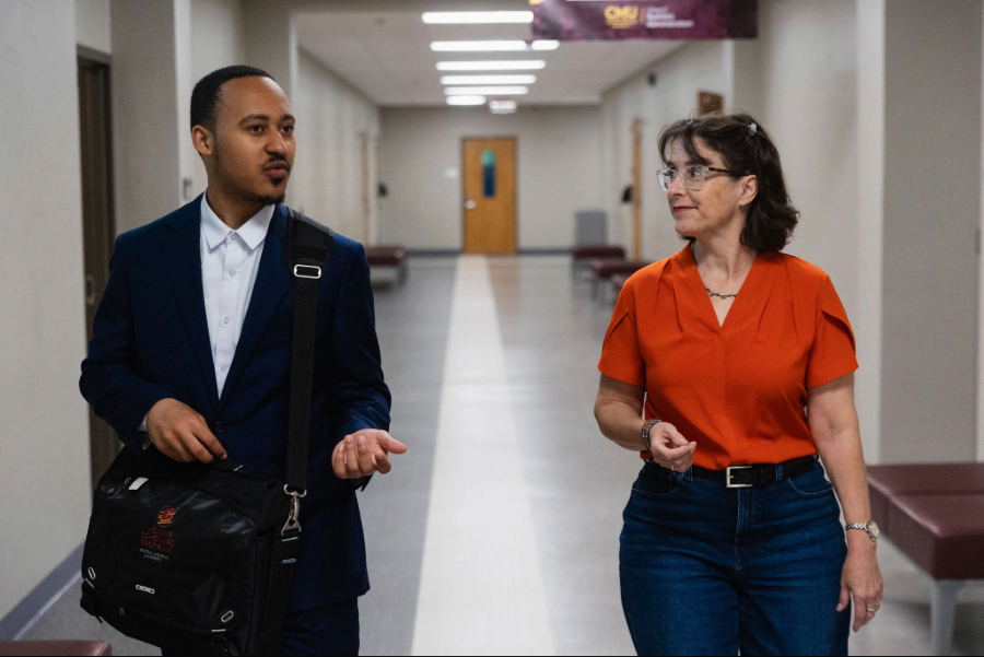 -26-05-20 Larry West w mentor Amy Swaney as-0035 (1) CMU Teacher walking with student through hallway and talking