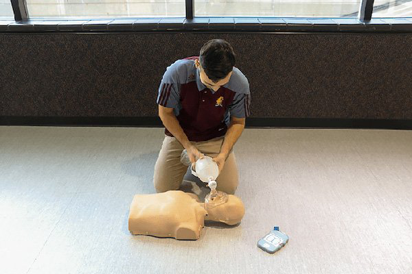 Instructor demonstrates CPR techniques on a dummy.