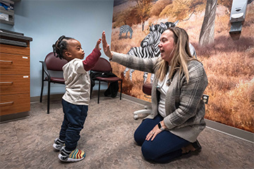 A woman and child giving high five in a medical patient office.