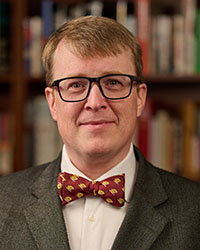 A smiling man with short brown hair parted on the side with glasses and a CMU bowtie.