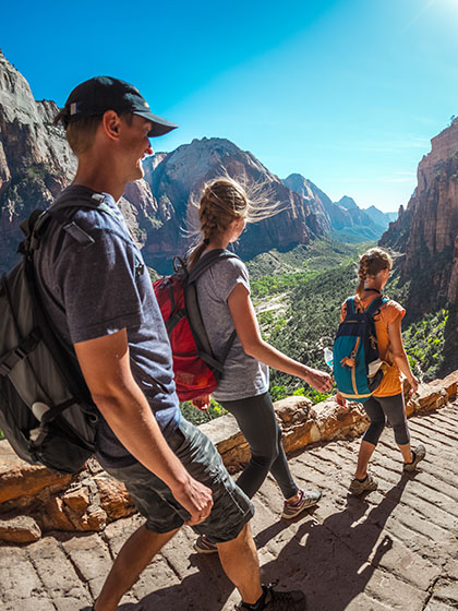 Three people hike down a brick path in Utah's Zion National Park.